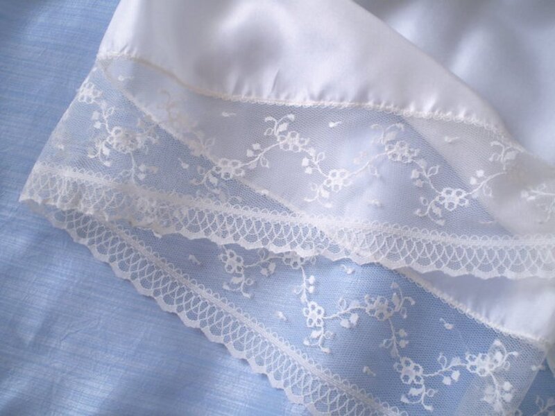 Detail shot of French-seamed lace hem on ivory satin christening gown — couture finishing, Kingdom Gowns Michigan
