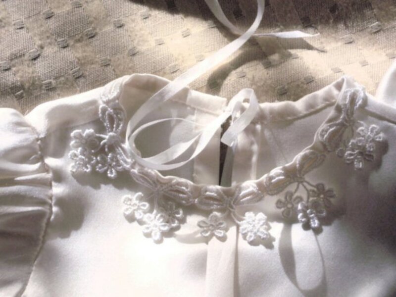 Close-up of ribbon tie closure and embroidered floral motif at christening gown neckline — Kingdom Gowns Michigan
