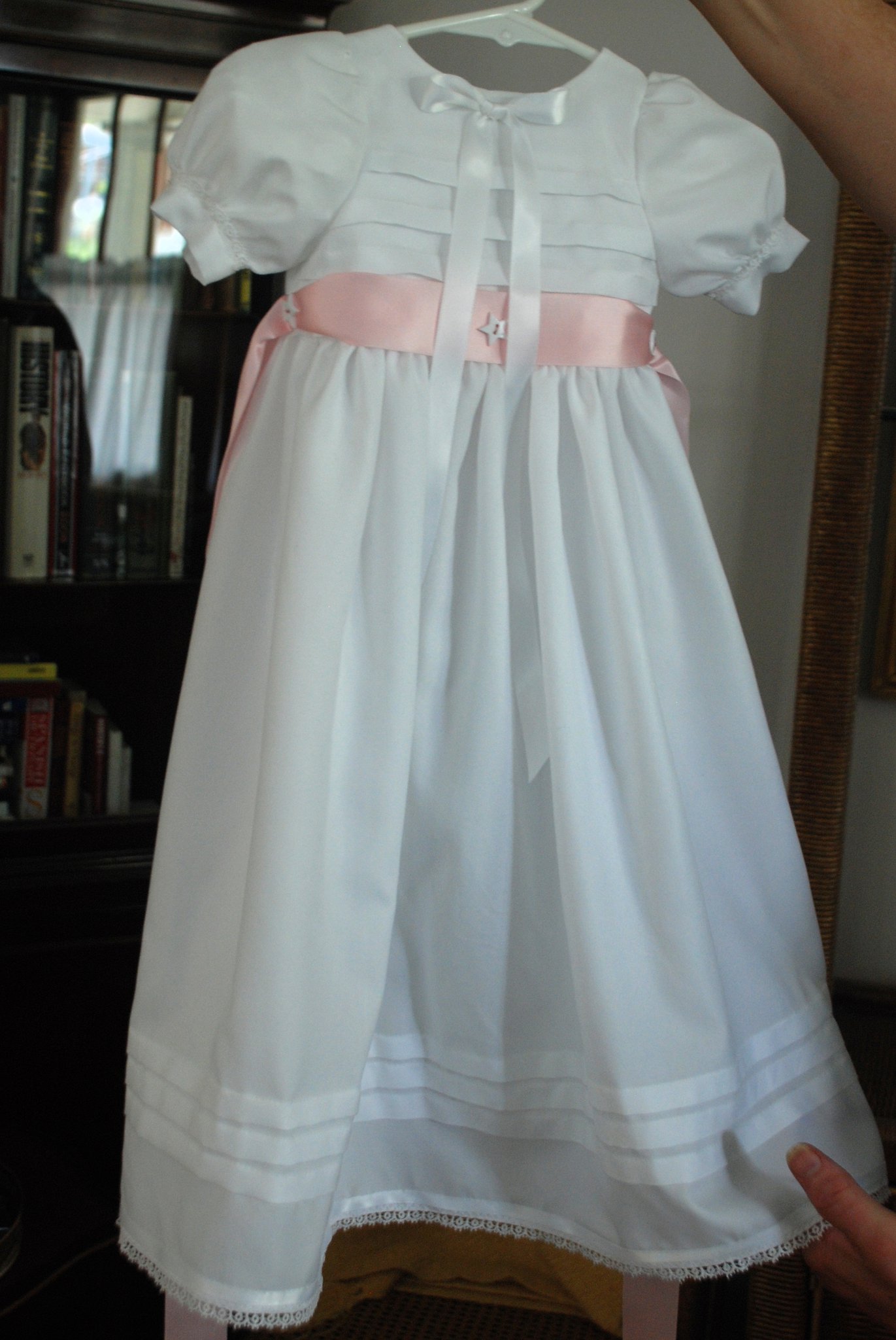 White organdy christening gown with pintucked bodice, wide pink sash ribbon, and lace-trimmed hem — Kingdom Gowns Michigan